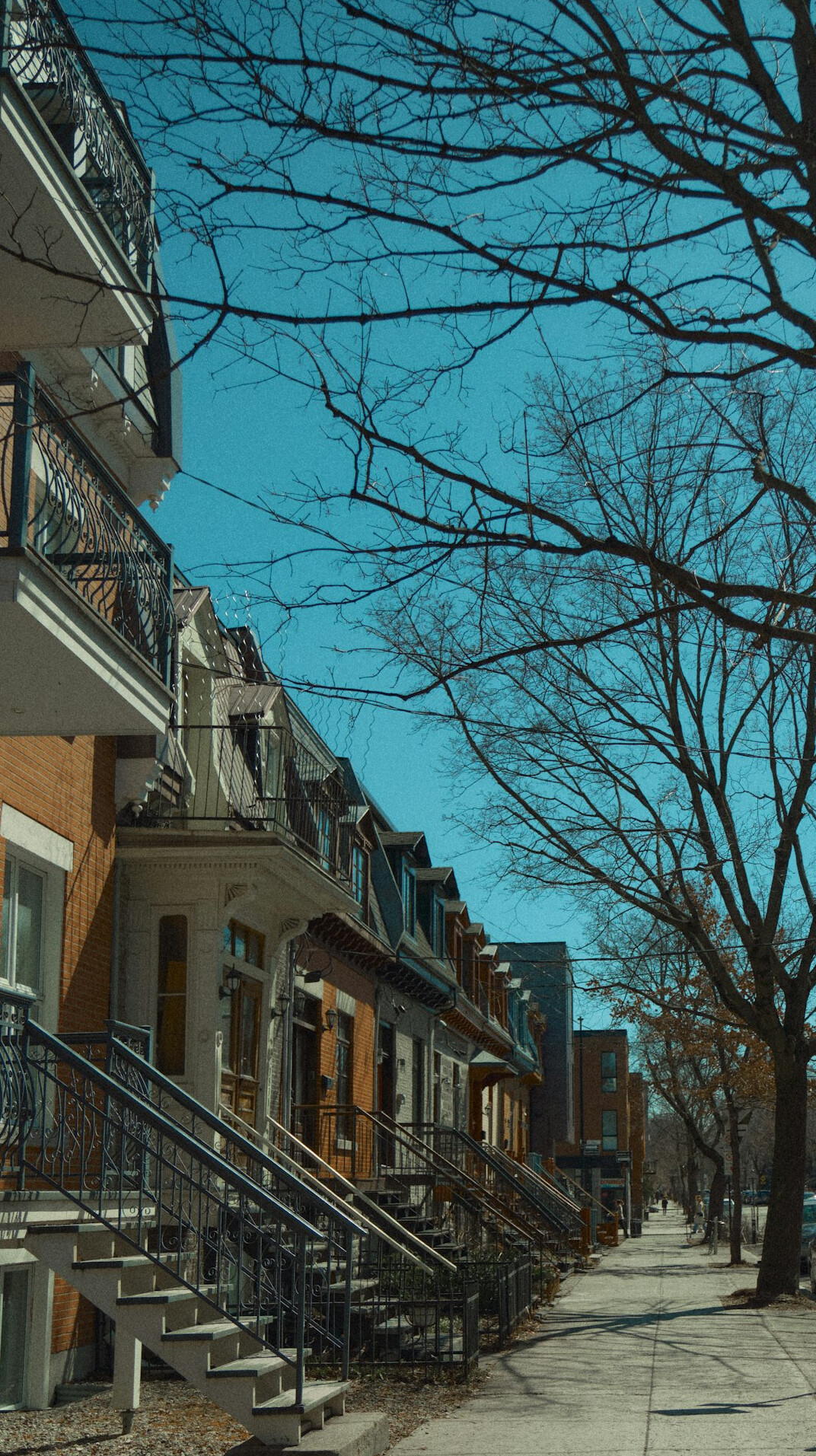 Row of colorful triplex apartment buildings with exterior spiral staircases in Montreal's Plateau neighborhood