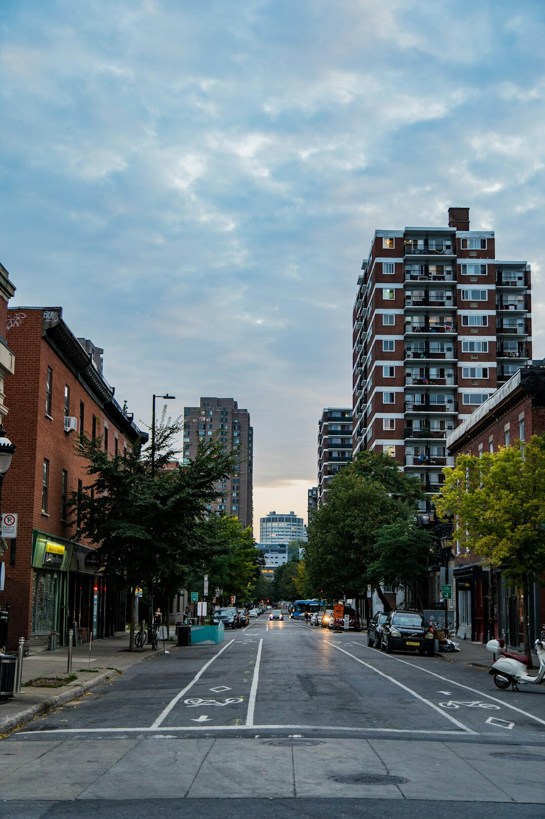 Wide street in a Canadian downtown neighborhood with pedestrians and row houses at dusk